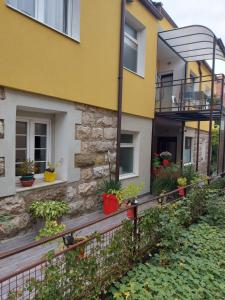 uma casa amarela com vasos de plantas ao lado em Guest House Pavlovic em Sokobanja