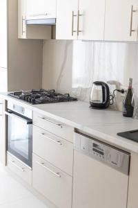 a white kitchen with a stove and white cabinets at RentWill apartments Milky Way in Chişinău +18 photos