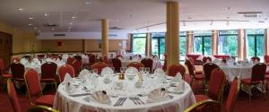 a banquet hall with white tables and red chairs at Logis H&ocirc;tel - Restaurant Le Tulipier in Vienne-le-Ch&acirc;teau