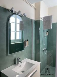 La salle de bains est pourvue d'un lavabo et d'une douche. dans l'établissement Hôtel Madame, à Bordeaux