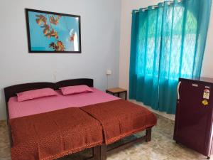 a bedroom with a bed and a blue curtain at Rosetta Guesthouse in Anjuna