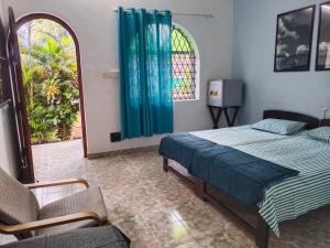 a bedroom with a bed and a chair and a window at Rosetta Guesthouse in Anjuna