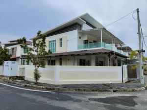 a white house with a white fence in front of it at Prestij 3 Homestay, Balik Pulau in Balik Pulau
