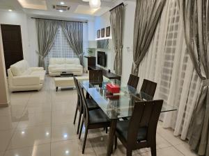 a living room with a glass table and chairs at Prestij 3 Homestay, Balik Pulau in Balik Pulau