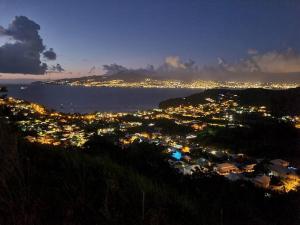 uma vista para uma cidade à noite com o oceano em VILLA EDINA , Exceptionnel aux Trois ILETS,T3 vue incroyable sur FDF em Les Trois-Îlets