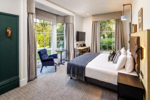 a hotel room with a bed and a chair and windows at Mercure Oxford Hawkwell House Hotel in Oxford