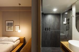uma casa de banho com um chuveiro, uma cama e um lavatório. em Maplewood Hotel Chiangmai em Chiang Mai