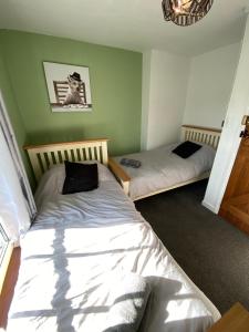 two beds in a room with green walls at Carlton Cottage Country Retreat - Perfect for Ipswich - Aldeburgh - Southwold - Thorpeness - Sizewell B - Sizewell C - Sleeps 13 in Little Glenham