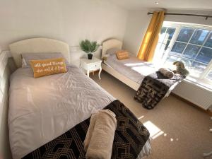 een slaapkamer met 2 bedden en een raam bij Carlton Cottage Country Retreat - Perfect for Ipswich - Aldeburgh - Southwold - Thorpeness - Sizewell B - Sizewell C - Sleeps 13 in Little Glenham