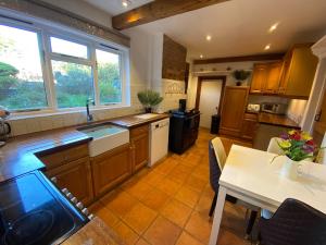 una cocina con armarios de madera y una mesa con comedor. en Carlton Cottage Country Retreat - Perfect for Ipswich - Aldeburgh - Southwold - Thorpeness - Sizewell B - Sizewell C - Sleeps 13 en Little Glenham