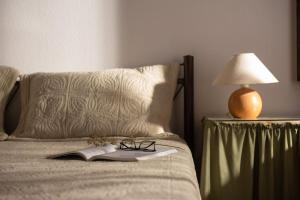 ein Bett mit einem Buch, einer Brille und einer Lampe in der Unterkunft Traditionelles Appartement ATHOS SHADOW am Meer in Paralia Sikias