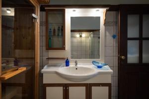 ein Badezimmer mit einem weißen Waschbecken und einem Spiegel in der Unterkunft Traditionelles Appartement ATHOS SHADOW am Meer in Paralia Sikias