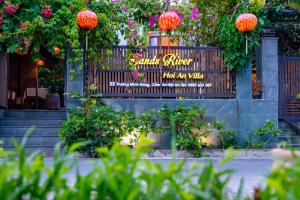 un panneau pour un restaurant avec des fleurs sur une clôture dans l'établissement Sands River Hoi An Villa, à Hội An