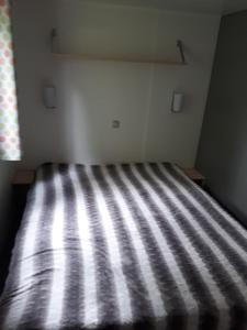 a bedroom with a striped bed with a window at CAMPING LA PINEDE in Les Mathes
