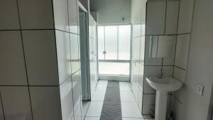 uma casa de banho branca com um lavatório e um espelho em Pousada Engenho do Vô em Camanducaia