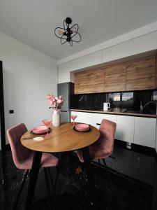 une table en bois dans une cuisine avec des chaises roses dans l'établissement Exclusive apartment Новобудова ЖК Театральний ЦЕНТР, à Rivne