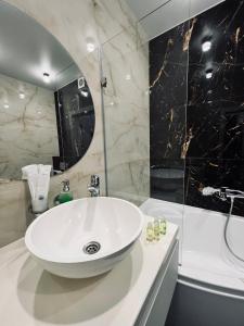 uma casa de banho com um lavatório branco e um chuveiro em Exclusive apartment Новобудова ЖК Театральний ЦЕНТР em Rivne