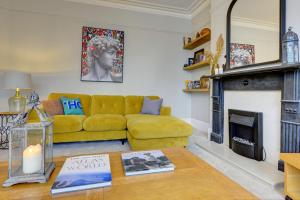 a living room with a yellow couch and a fireplace at Stylish 2 Bedroom Maisonette With Parking in Harrogate