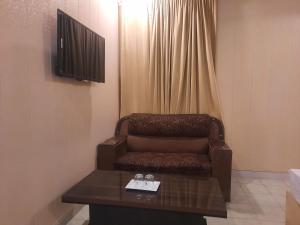 een kamer met een stoel, een tafel en een televisie bij Royal Fort Executive Hotel Gulberg in Lahore