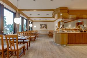 a restaurant with tables and chairs and a kitchen at Hotel Schomacker in Lilienthal
