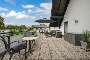 eine Terrasse mit Stühlen, Tischen und einem Sonnenschirm in der Unterkunft Hotel Schomacker in Lilienthal