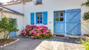 een huis met blauwe deuren en roze bloemen bij Belle maison avec piscine privée in Saint-Pierre-Quiberon