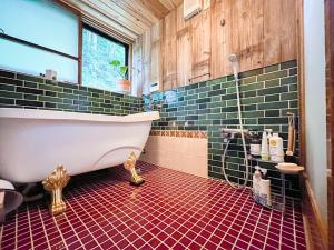 bagno con vasca e pavimento piastrellato rosso di 古民家宿Tani House Itaya -セルフチェックイン a Tokamachi