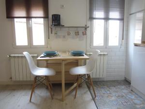 a kitchen with a wooden table and two white chairs at Loló Vivienda de uso Turístico 09-27 in Burgos