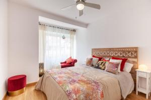 TarracoHomes, TH163 Apartamento Via Augusta vistas al mar في تاراغونا: غرفة نوم بسرير كبير وكرسي احمر