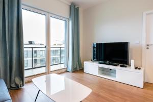 a living room with a tv and a large window at Wola Lush Apartment in Warsaw