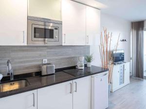 a white kitchen with a sink and a microwave at Studio Hendaye, 1 pièce, 4 personnes - FR-1-2-286 in Hendaye