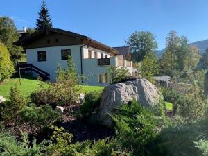 una casa con una gran roca delante de ella en Alpenvilla Berchtesgaden Appartements en Berchtesgaden