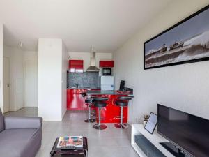 a living room with a couch and a red kitchen at Appartement Hendaye, 2 pièces, 4 personnes - FR-1-2-308 in Hendaye