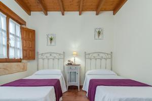 two beds in a room with white walls and wooden ceilings at El rincón de Lalo in Prases