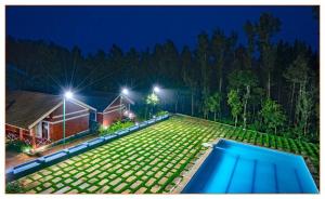 a backyard with a swimming pool at night at Nexstay Coffee Grove Resort in Chikmagalūr