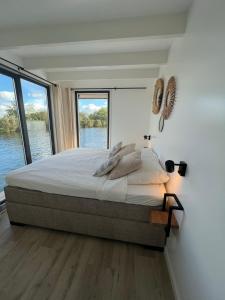 a bedroom with a large bed with a large window at Surla houseboat "Aqua Zen" Kagerplassen with tender in Kaag