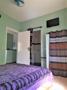 ein Schlafzimmer mit einem lila Bett und einer Dusche in der Unterkunft Auberge Le Baobab in Saly Portudal