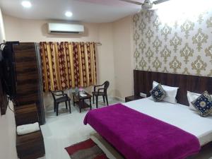 a bedroom with a large bed with a purple blanket at Laxmi Mahal in Udaipur