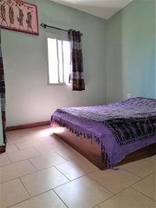 1 dormitorio con cama, ventana y suelo de baldosa en Auberge Le Baobab en Saly Portudal