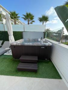 einen Whirlpool auf einem Balkon mit Gras und Palmen in der Unterkunft Estepona Luxe top appartement in finca de cortesin d38 in Estepona