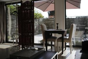 una sala da pranzo con tavolo, sedie e ombrellone di The Suite Escape Suite Wood a Sint-Lievens-Houtem