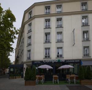 un hôtel avec des tables et des parasols devant lui dans l'établissement CAMPANILE PARIS - Clichy Centre, à Clichy