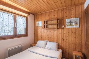 ムジェーヴにあるCharming flat with balcony at the foot of the slopes in Megève - Welkeysの木製の壁のベッドルーム1室(ベッド1台付)