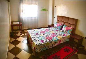 a bedroom with a bed with a flowered comforter at ZELLAKA hôtel & café in Khouribga