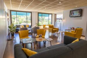 a waiting room with couches and tables and chairs at Kyriad Blois Sud in Vineuil