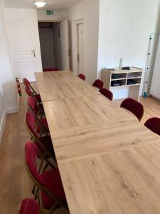 une salle de conférence avec une grande table en bois et des chaises rouges dans l'établissement Logement de groupe à Villandry avec terrasse, à Villandry