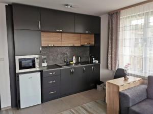 a kitchen with black cabinets and a sink and a couch at Апартамент Time for us in Velingrad