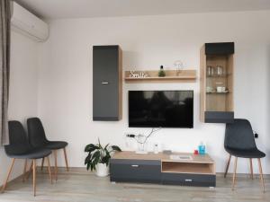 ein Wohnzimmer mit zwei schwarzen Stühlen und einem TV in der Unterkunft Апартамент Time for us in Welingrad