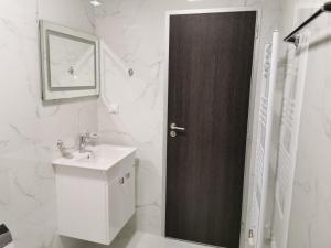 ein Badezimmer mit einem Waschbecken und einer Holztür in der Unterkunft Апартамент Time for us in Welingrad