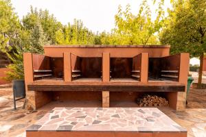 un banc en bois assis à côté d'un foyer extérieur dans l'établissement Bodega Andrés Iniesta con visita y cata, à Fuentealbilla